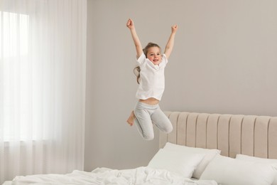 Cute little girl jumping on bed at home