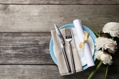 Photo of Stylish table setting with cutlery and flowers on wooden background, flat lay. Space for text