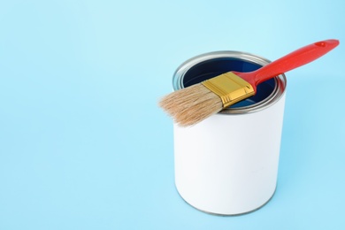Photo of Open can of paint with brush on color background. Space for text