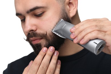 Photo of Handsome young man trimming beard on white background, closeup