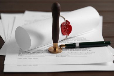 Photo of Notary contract. Documents, wax stamp and pen on table