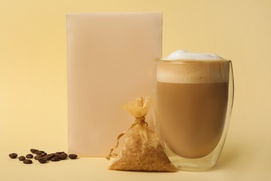 Photo of Scented sachets, cup of latte and coffee beans on beige background