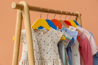 Rack with stylish children clothes on beige background, closeup