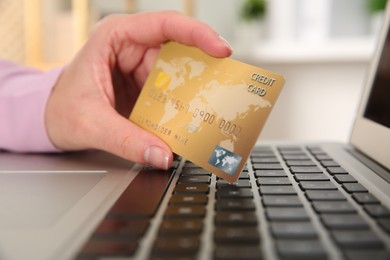 Photo of Online payment. Woman using credit card and laptop indoors, closeup
