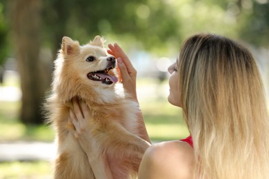 Young woman with her cute dog in park on sunny day