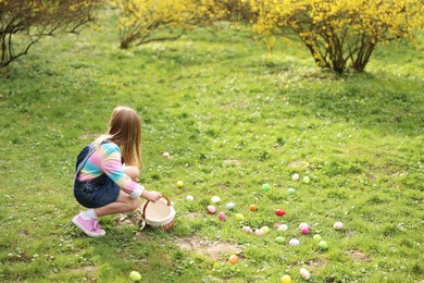 Photo of Easter celebration. Cute little girl hunting eggs outdoors