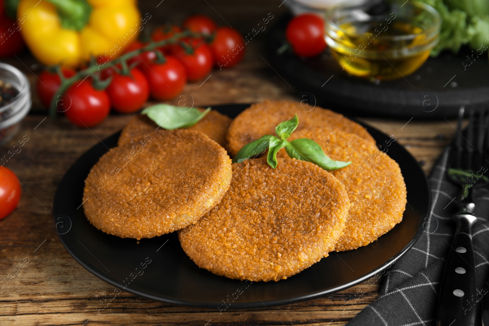 Photo of Delicious fried breaded cutlets with basil on wooden table, closeup