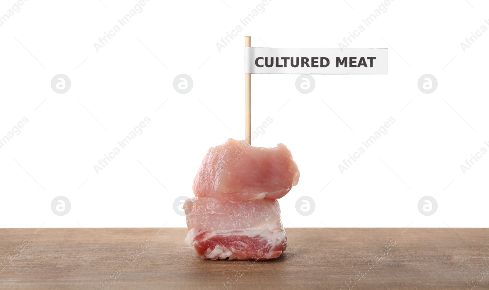 Photo of Pieces of raw cultured meat with toothpick label on wooden table against white background