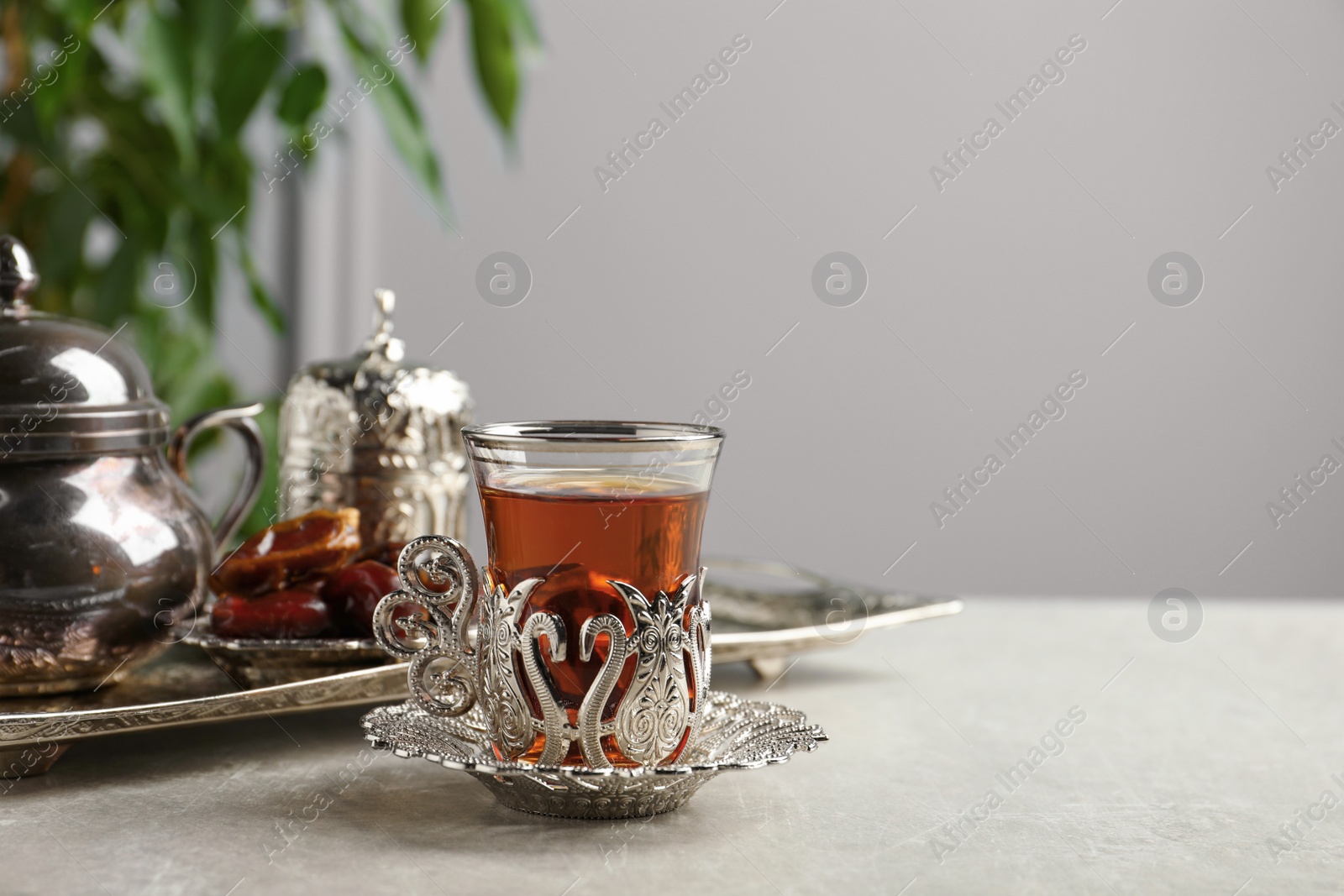 Photo of Tea and date fruits served in vintage tea set on grey table, space for text