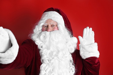 Photo of Authentic Santa Claus taking selfie on red background