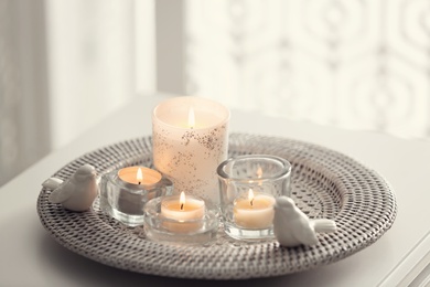 Photo of Beautiful burning candles on tray against light background