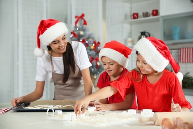 Photo of Happy family with Santa hats cooking in kitchen. Christmas time