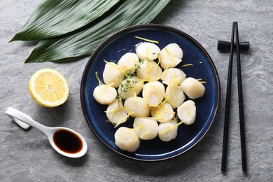 Photo of Raw scallops with thyme and lemon zest served on grey marble table, flat lay