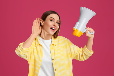 Young woman with megaphone on pink background