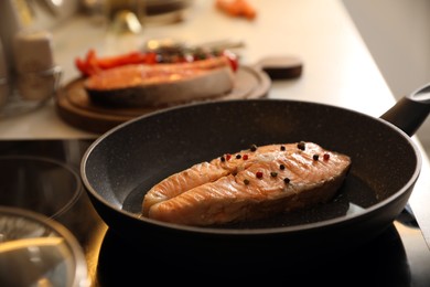 Photo of Frying pan with tasty salmon steak on cooktop