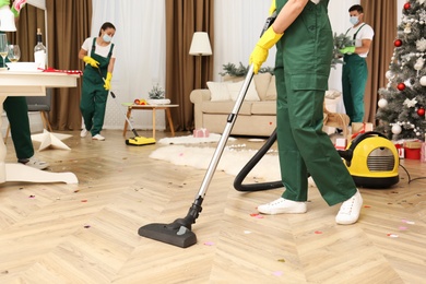 Cleaning service team working in messy room after New Year party