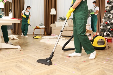 Photo of Cleaning service team working in messy room after New Year party