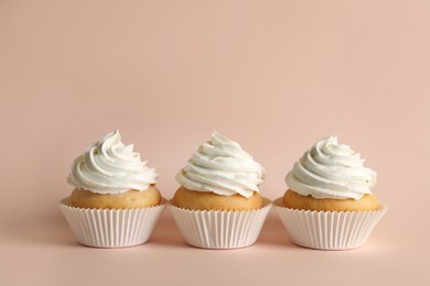 Delicious cupcakes with white cream on pink background