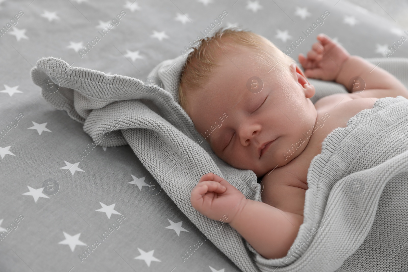 Photo of Cute little baby under soft plaid sleeping on bed