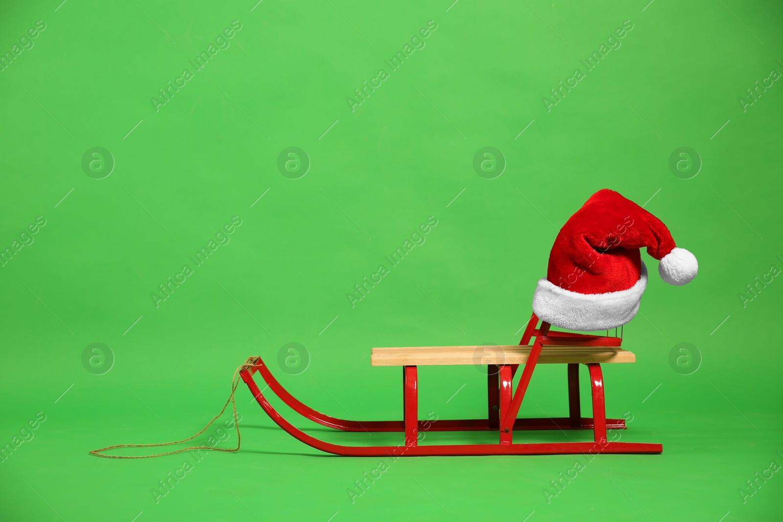 Photo of Sleigh with Santa hat on green background. Space for text