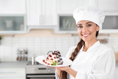 Photo of Professional female chef with plate of delicious dessert in kitchen