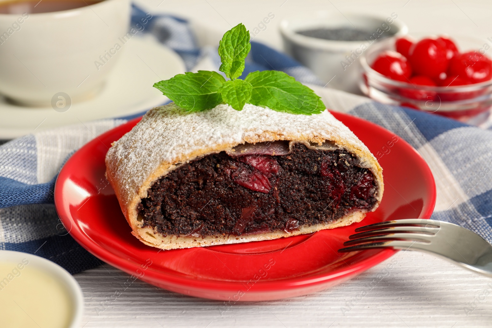 Photo of Delicious strudel with cherries and poppy seeds on white wooden table, closeup