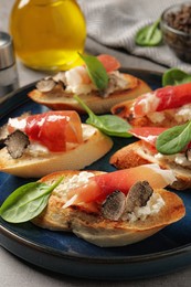 Delicious bruschettas with cheese, prosciutto and slices of black truffle on table, closeup