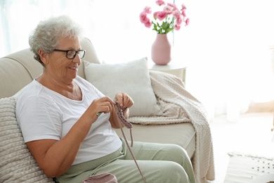 Photo of Elderly woman crocheting at home. Creative hobby