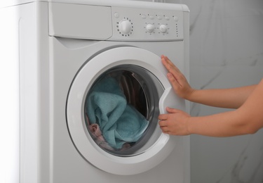 Photo of Woman opening modern washing machine indoors, closeup
