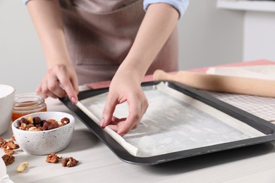 Woman making delicious baklava at white wooden table, closeup