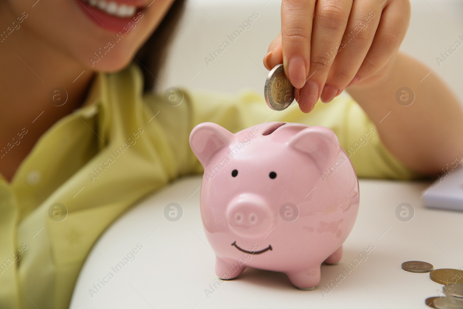 Photo of Woman putting coin into piggy bank indoors, closeup. Money savings