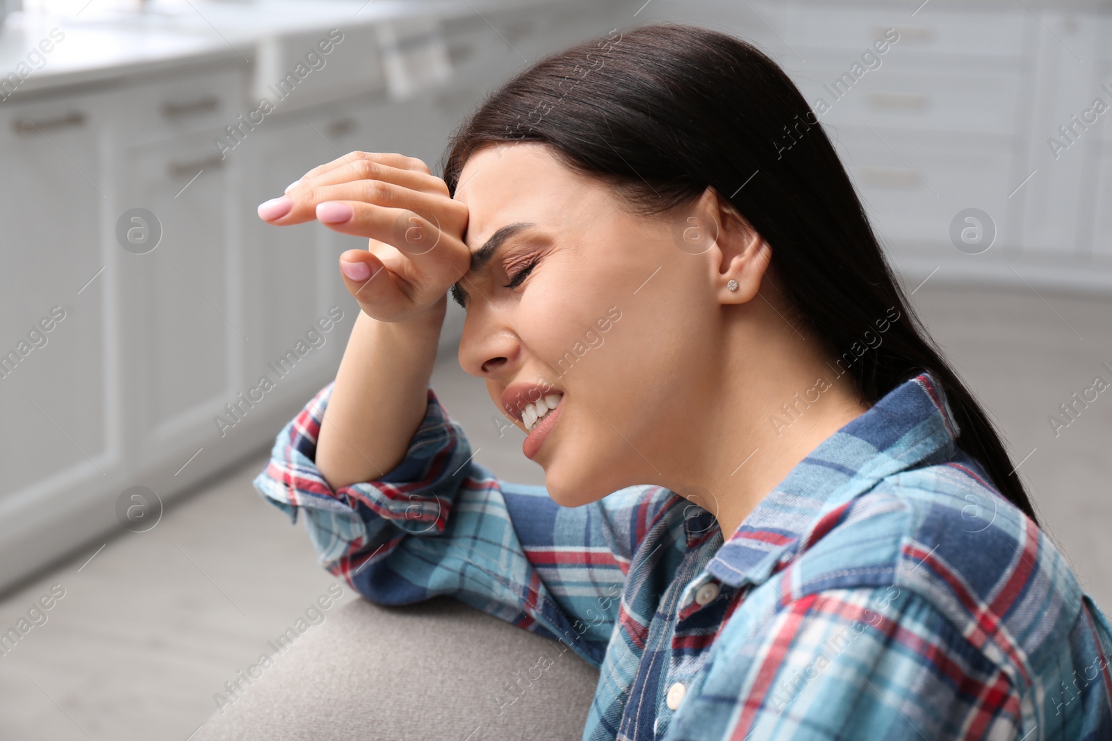 Photo of Young woman suffering from migraine at home