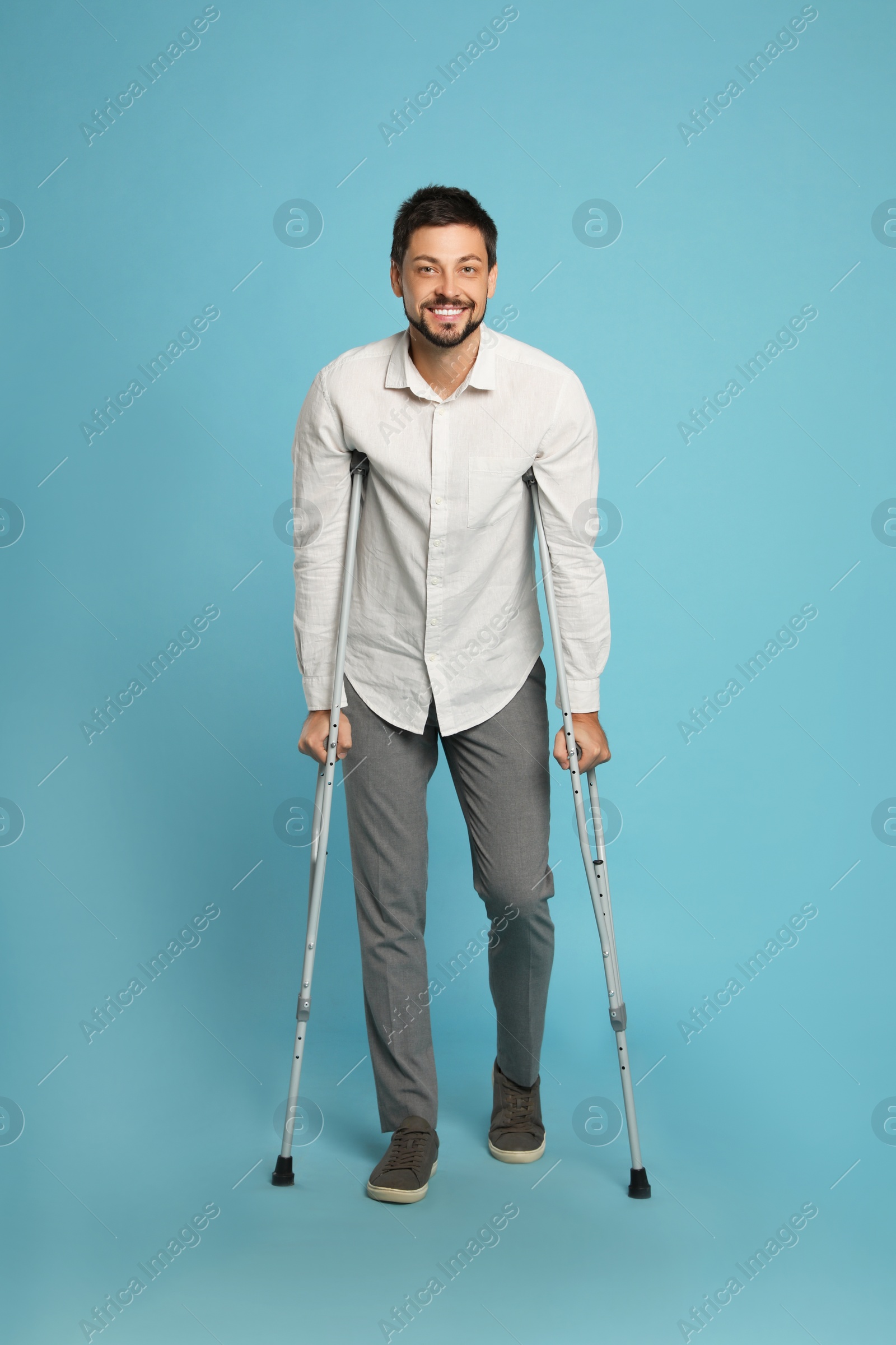 Photo of Full length portrait of man with crutches on light blue background