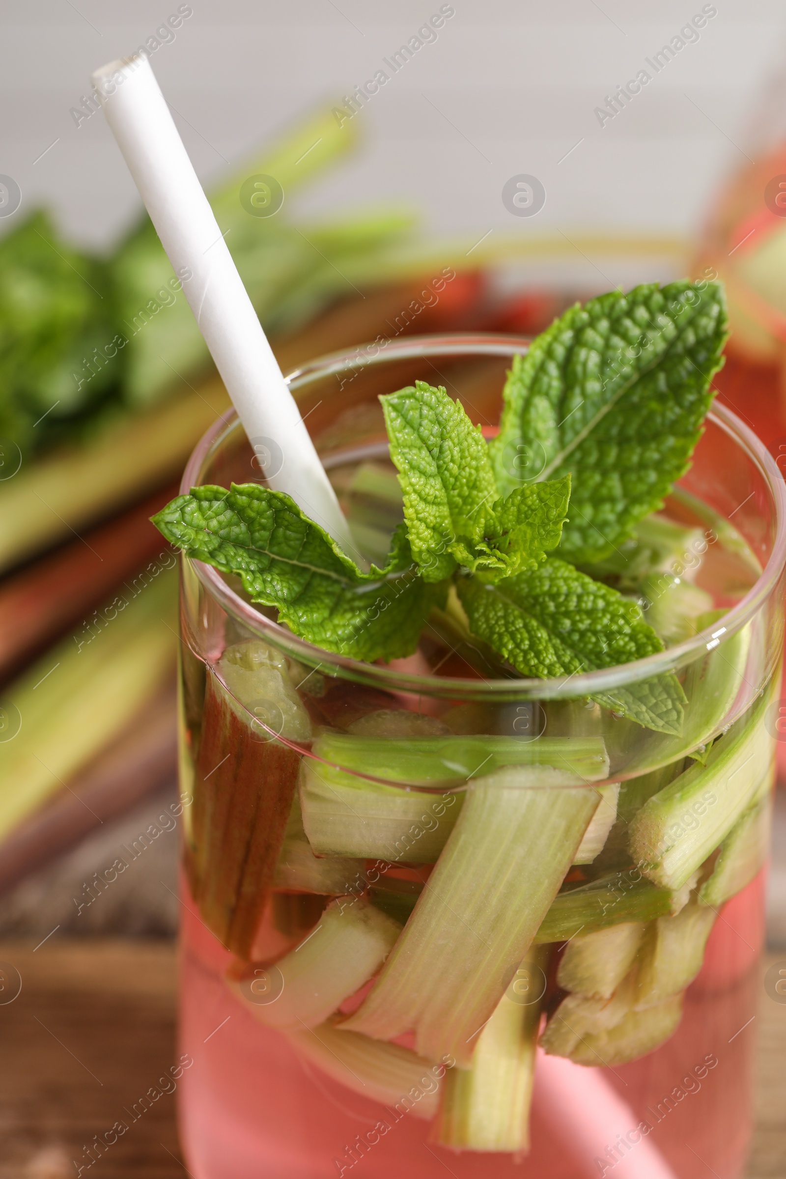 Photo of Glass of tasty rhubarb cocktail on blurred background, closeup
