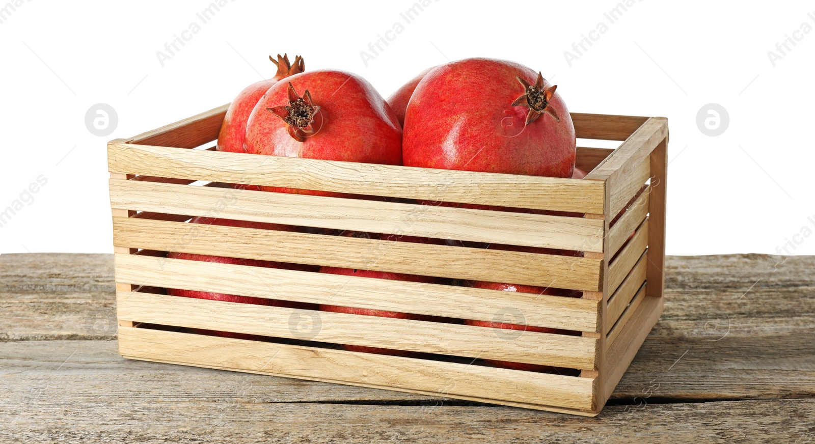 Photo of Fresh pomegranates in crate on wooden table against white background