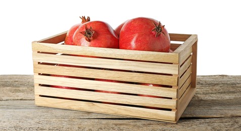 Photo of Fresh pomegranates in crate on wooden table against white background