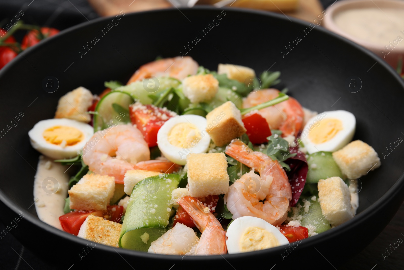 Photo of Delicious Caesar salad with shrimps in bowl, closeup