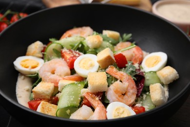 Photo of Delicious Caesar salad with shrimps in bowl, closeup