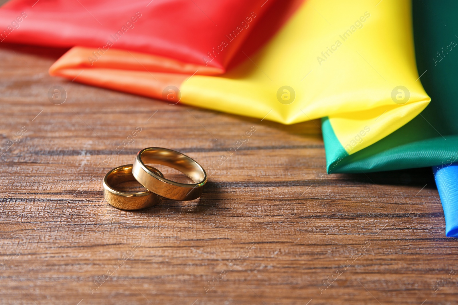 Photo of Wedding rings and rainbow flag on wooden table. Gay marriage