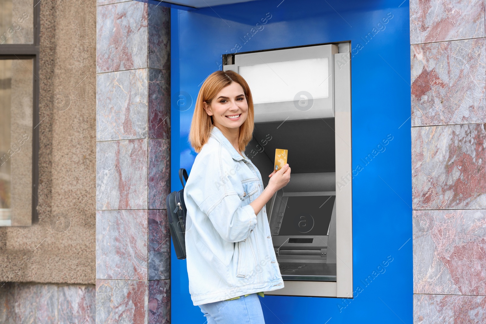 Photo of Beautiful woman with credit card near cash machine outdoors