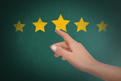 Quality evaluation. Woman touching golden star on green chalkboard, closeup