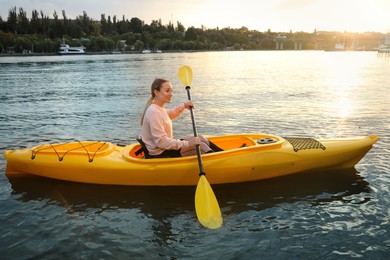 Beautiful young woman kayaking in river. Summer activity