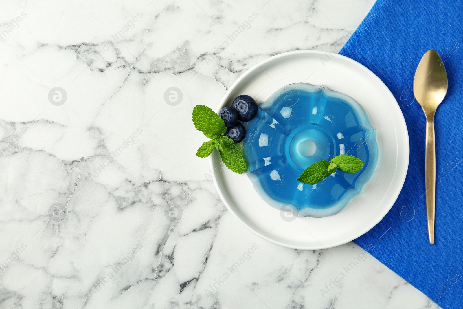 Photo of Plate of delicious blue jelly with berries on marble background, top view. Space for text