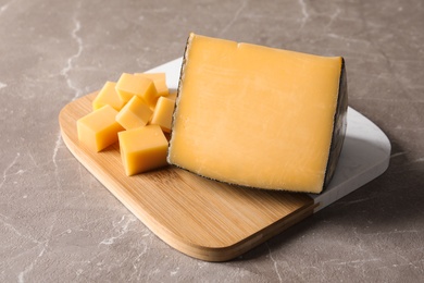 Board with delicious cut cheese on marble table