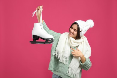 Happy woman with ice skates on pink background