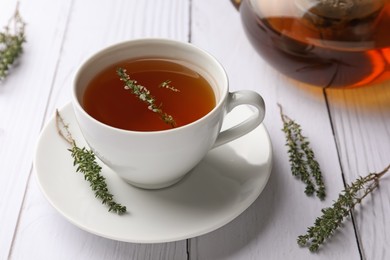 Aromatic herbal tea with thyme on white wooden table