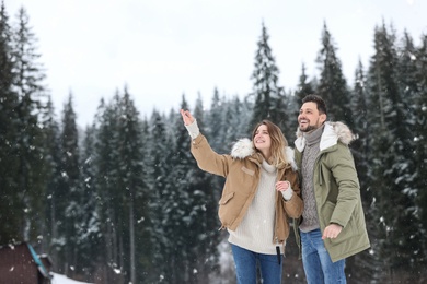Couple spending time outdoors on snowy day, space for text. Winter vacation