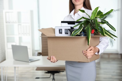 Young woman holding box with stuff at office, closeup