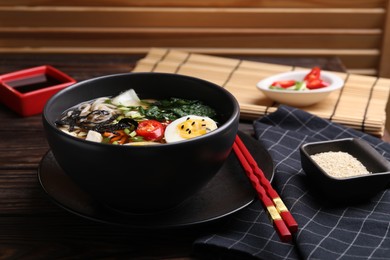 Photo of Delicious vegetarian ramen served on wooden table, closeup. Noodle soup