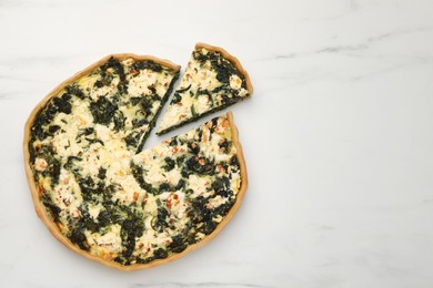 Delicious homemade spinach quiche on white marble table, flat lay. Space for text